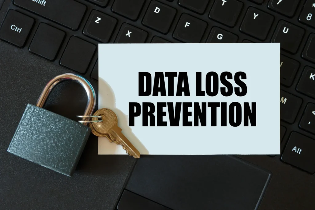 Et tastatur med en hængelås og en nøgle placeret ovenpå. Ved siden af hængelåsen er et skilt med teksten "DATA LOSS PREVENTION". Billedet symboliserer datasikkerhed og beskyttelse mod datatab.